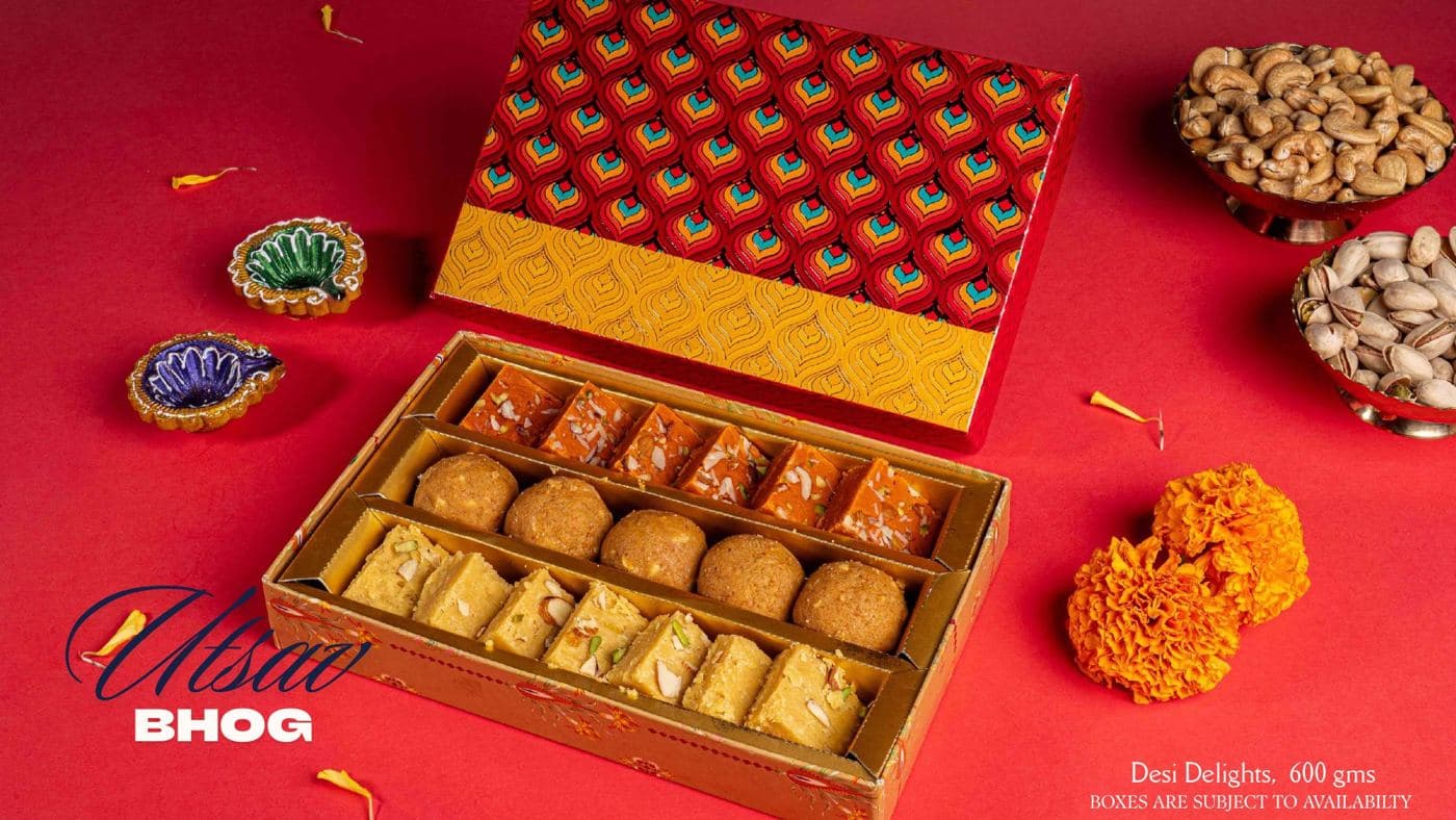 The Utsav Bhog box from Chhappan Bhog, with ladoos and halwa squares under a red patterned lid
