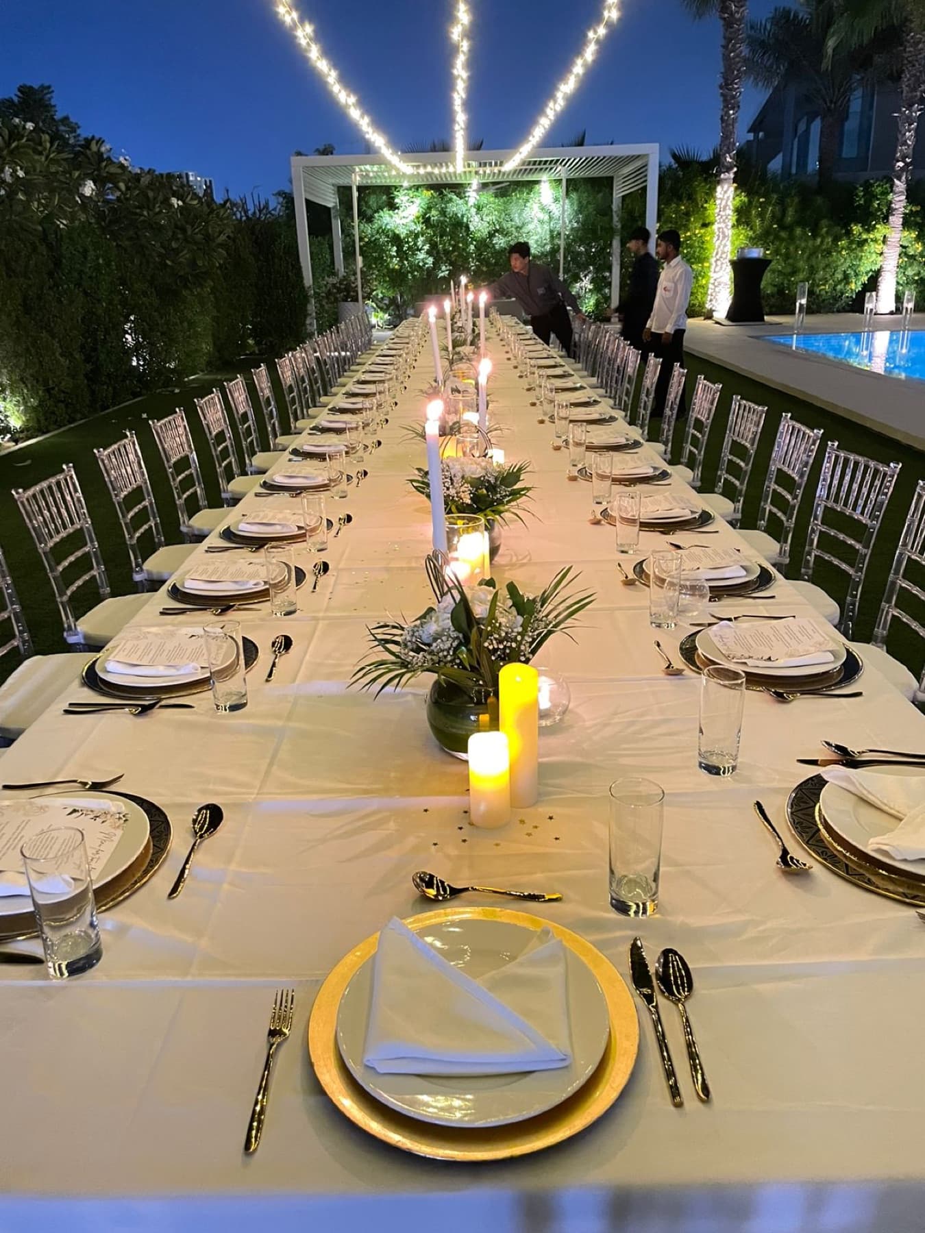 A candlelit long-table wedding dinner in a garden venue, styled by Cater Inc. in Abu Dhabi
