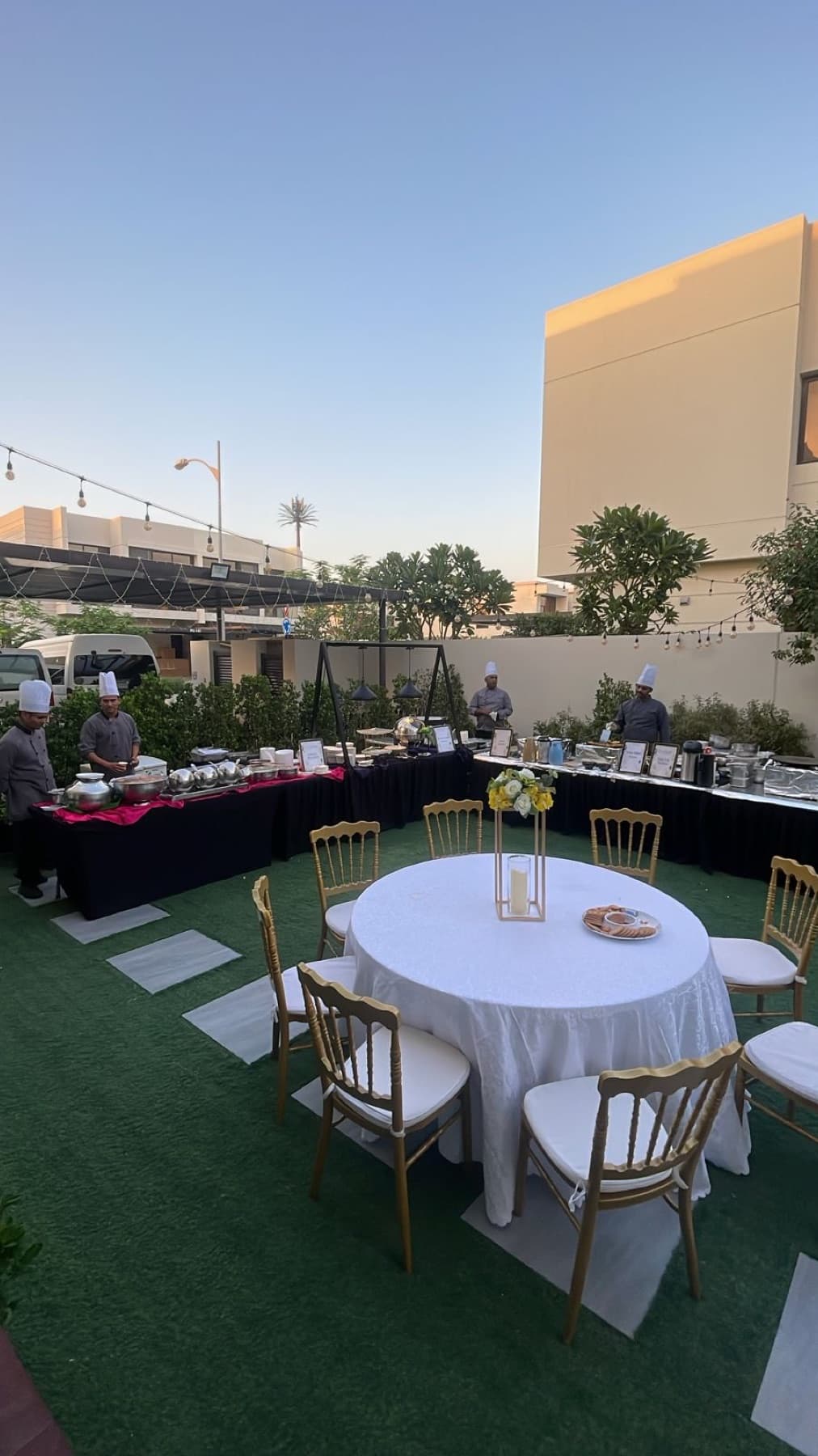 A Cater Inc. team setting up an outdoor garden dinner in Dubai at dusk