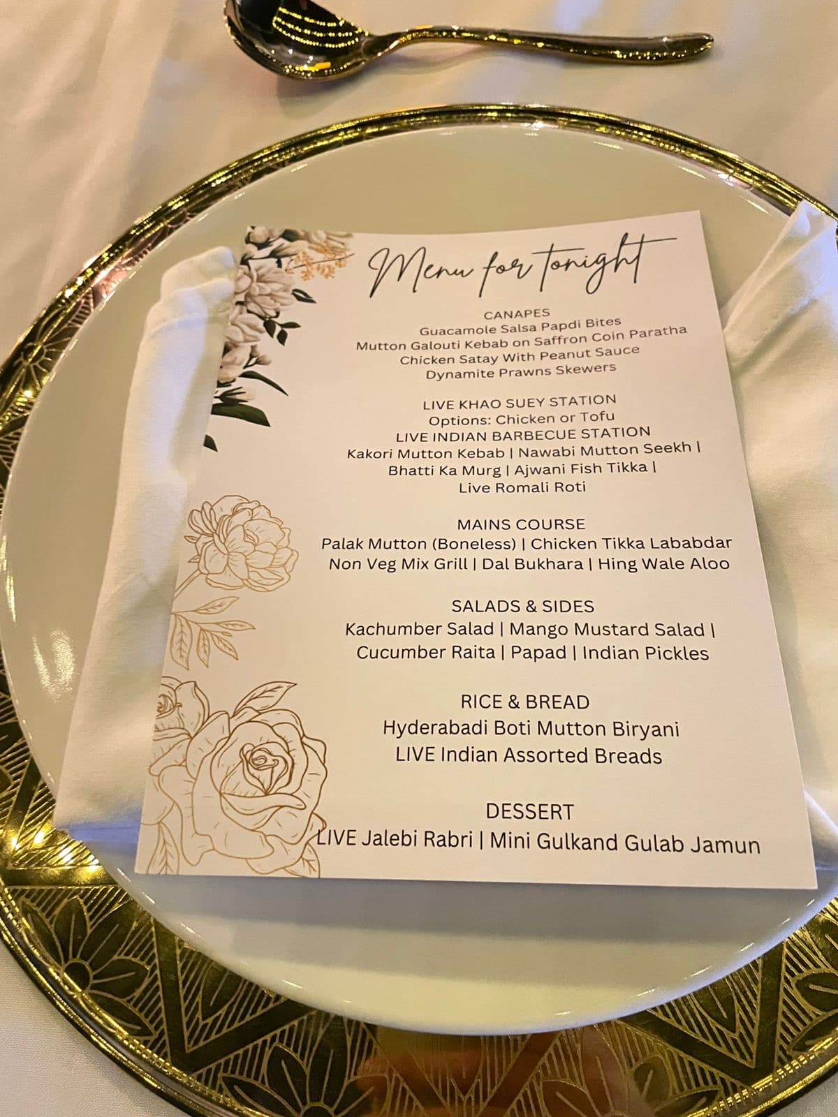 An elegant hand-lettered menu card on a gold charger plate at a Cater Inc. dinner